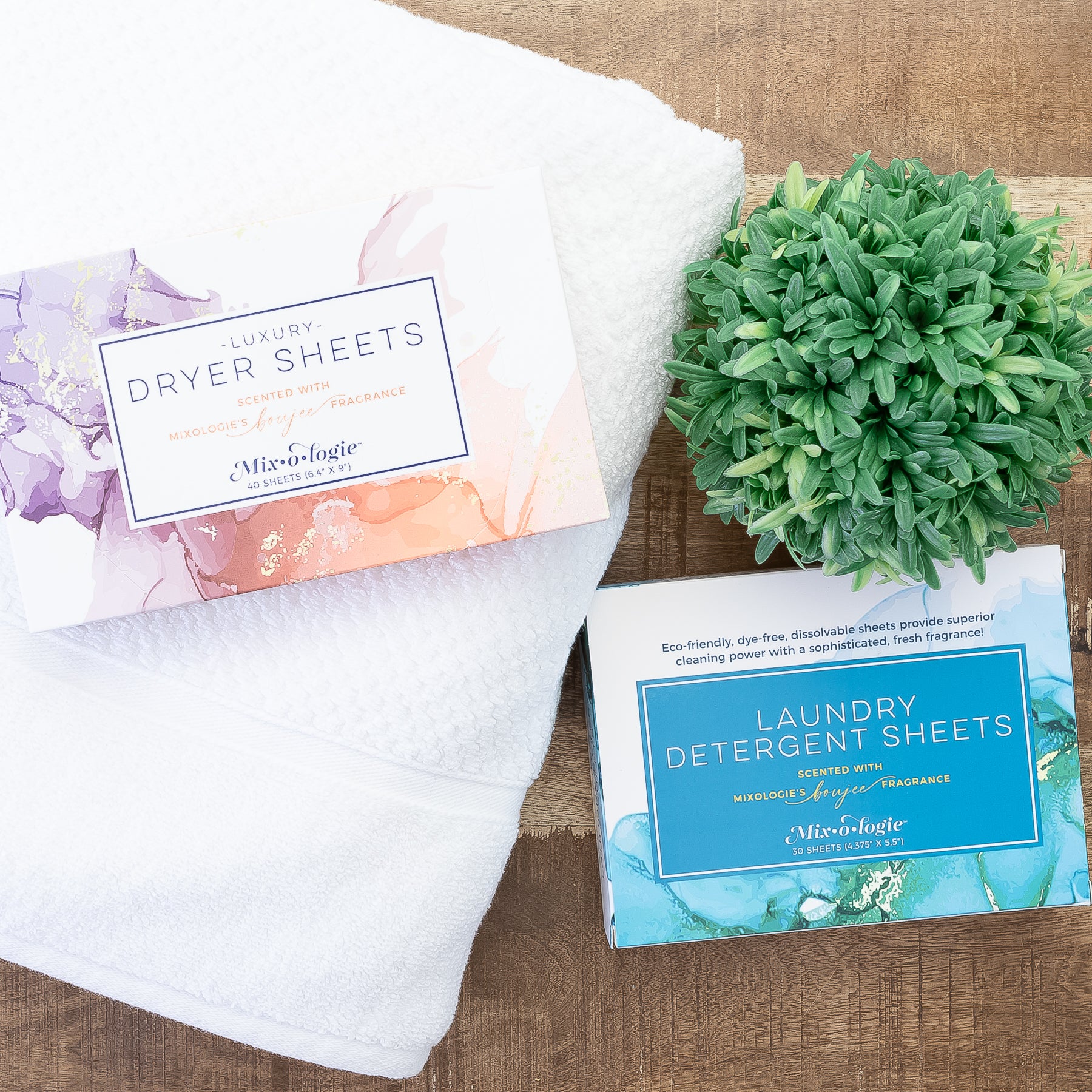 Boujee Laundry Detergent Sheets and Dryer Sheets in packaging on white towel with greenery