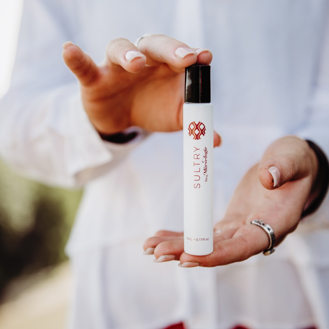 Rollerball Perfume in Sultry (wild musk) scent being held by woman wearing a white shirt.