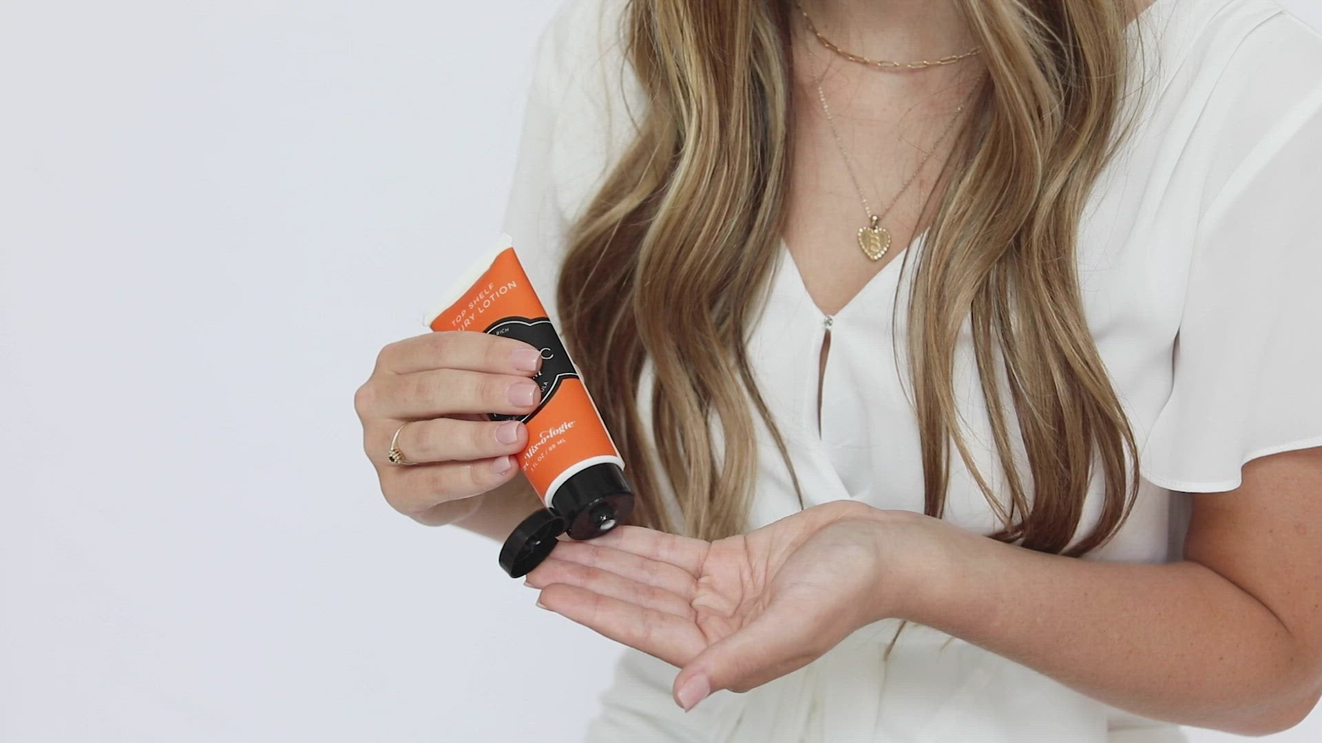 Mixologie's top shelf luxury lotion scented with Electric (citrus twist) in 3 mL plastic tube being applied to model's hands