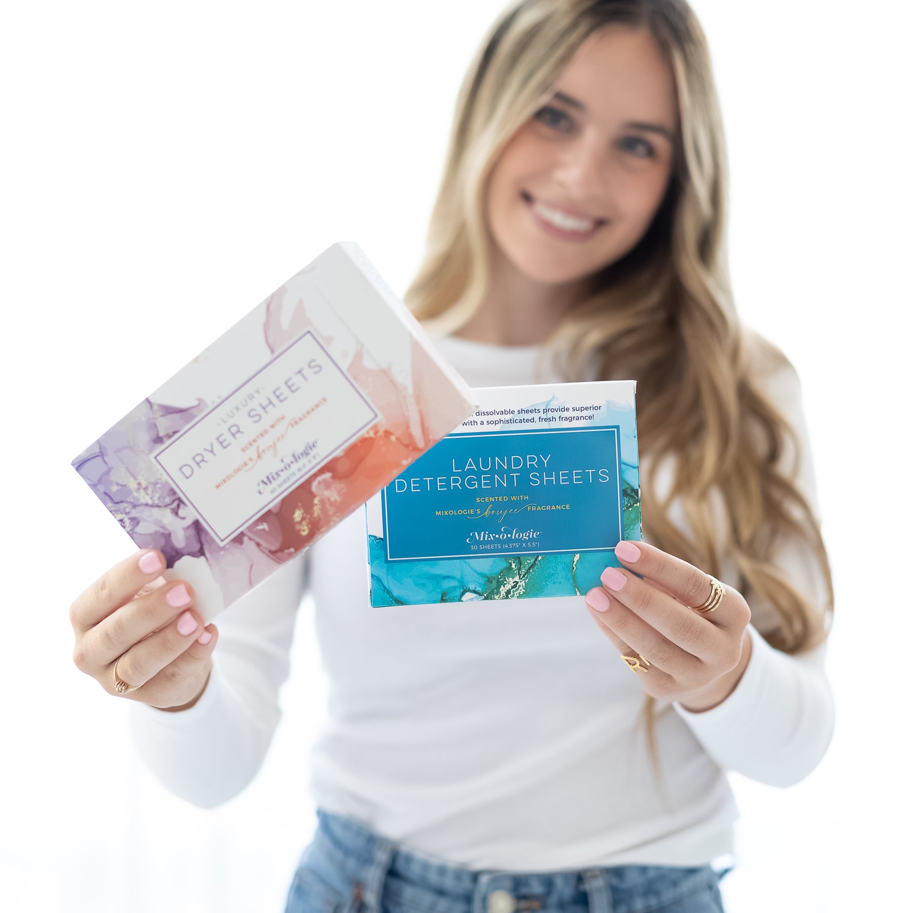 Luxury dryer sheets scented with Mixologie's Boujee fragrance. 40 of the 6.4"X9" sized sheets in rectangle box. Being held by model with detergent sheets.