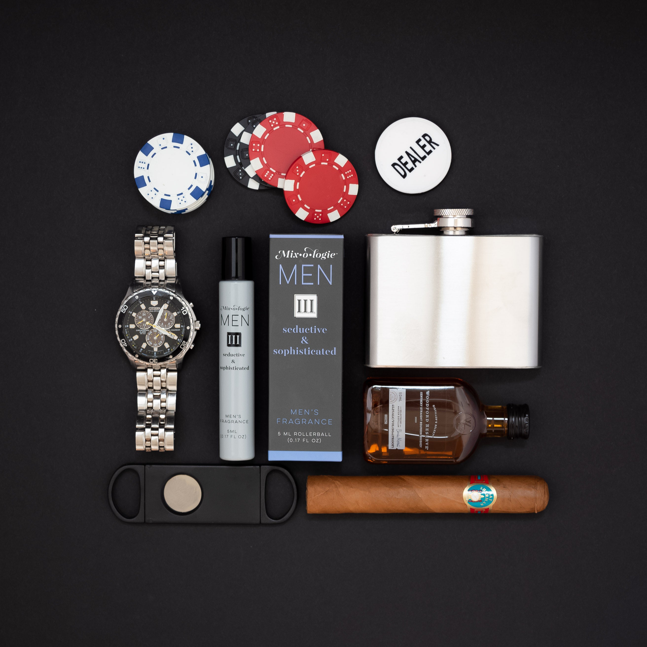 Mixologie rollerball scented with Men's III (seductive & sophisticated) fragrance in 5 mL glass bottle displayed with whiskey, cigar, watch, and poker chips.
